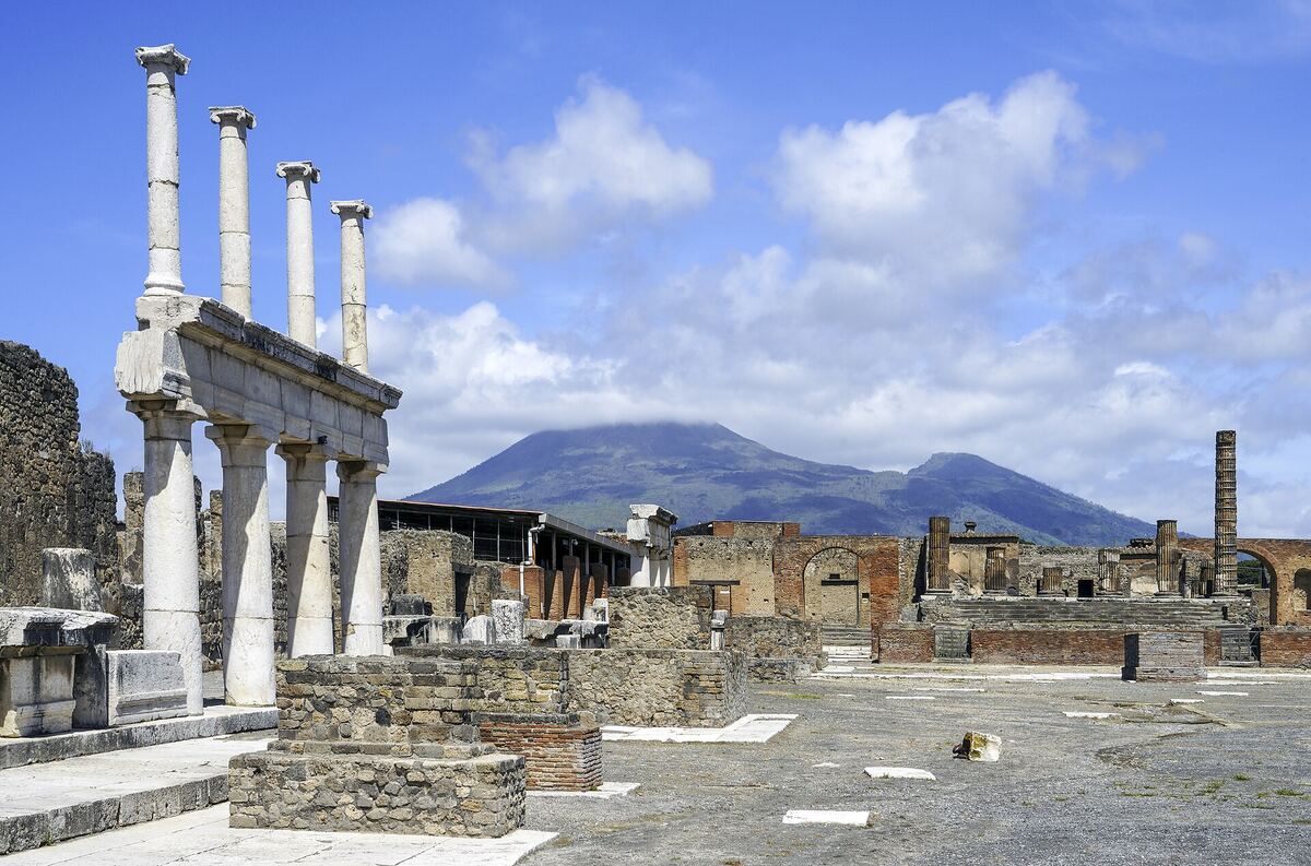 Colunas e ruínas do Fórum de Pompeia com o cone do monte Vesúvio ao fundo