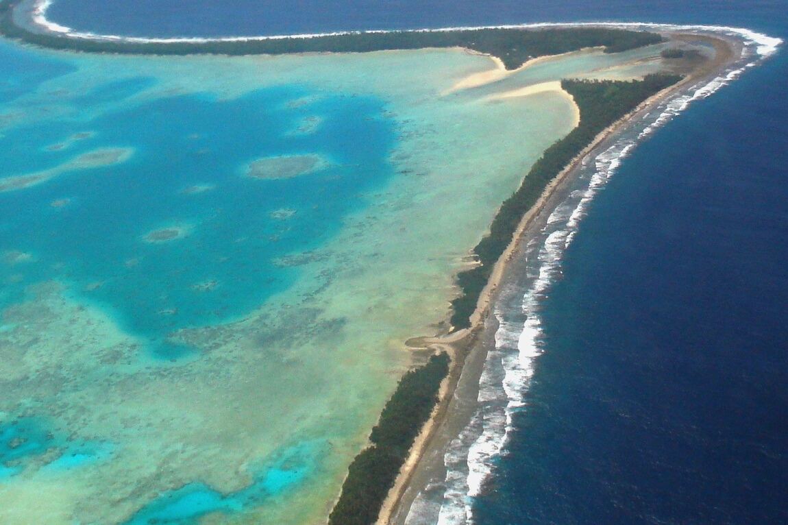 Veduta aerea di una stretta lingua di terra tra una laguna turchese e il blu scuro dell'oceano Pacifico sull'atollo di Funafuti